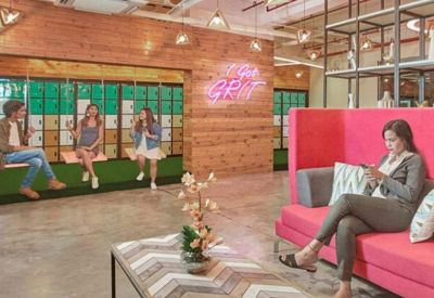 Relaxed coworking zone with indoor swings, a pink high-back sofa, and warm wood-paneled walls.