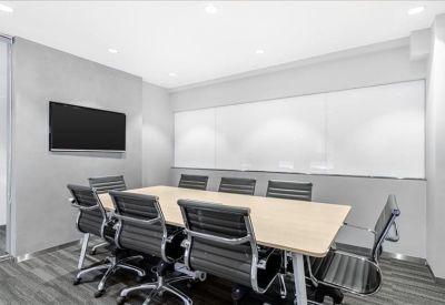 Modern conference room featuring a large table, black ergonomic chairs, and a wall-mounted screen.