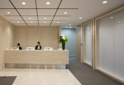 Bright reception area with light wood paneling and a large floral arrangement.