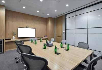 Modern meeting room with a wooden table, ergonomic chairs, and a wall-mounted monitor.