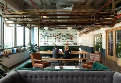 Open-plan coworking area with long wooden tables and a decorative boat hung from the ceiling.