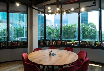 Sunlit circular meeting room with red chairs and floor-to-ceiling windows.