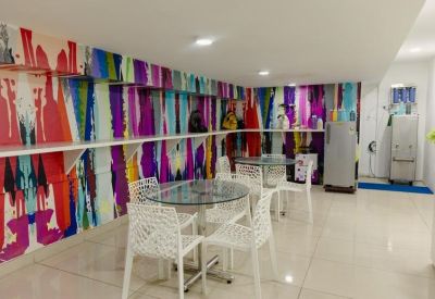Communal break area with glass tables, white patterned chairs, and a vibrant multi-colored wall mural.