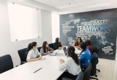 Professional meeting room with a large white table and a word-cloud feature wall highlighting teamwork.
