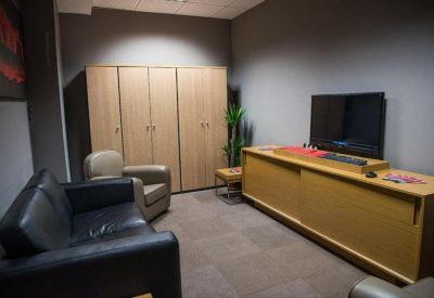 Comfortable lounge area with black leather sofa, wooden cabinets, and a television.