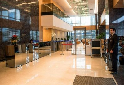Spacious marble lobby with a reflective reception desk and security personnel.