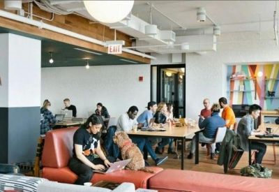 Open-plan office space with long tables and a casual seating area.
