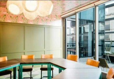 Meeting room with wooden tables, orange chairs, and a floral feature wall.