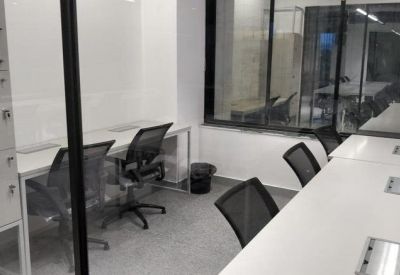 Compact private office with white desks and black mesh chairs.