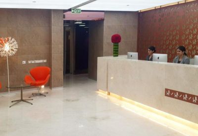 Modern reception lobby with warm lighting, wood paneling, and an orange accent chair.