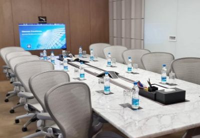 Bright conference room with a marble table and video conferencing screen.