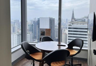 Small round meeting table with four black and orange chairs by a large window.