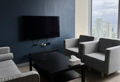 Casual lounge area with grey armchairs, a coffee table, and a wall-mounted TV.