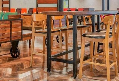 Rustic communal area featuring a wooden cart and high-top tables with wooden bar stools.