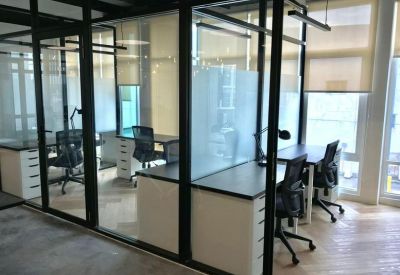 Private glass-walled office suites with white desks and black ergonomic chairs.