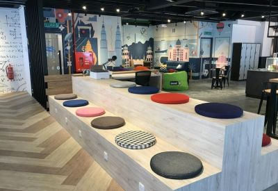 Tiered wooden seating area with colorful round cushions and vibrant wall graphics.