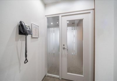 Clean white reception area featuring a wall-mounted telephone and frosted glass door.