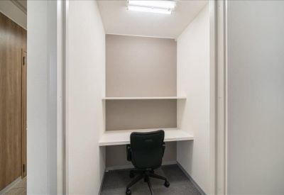 Private single-person workstation booth with a white desk and black ergonomic chair.
