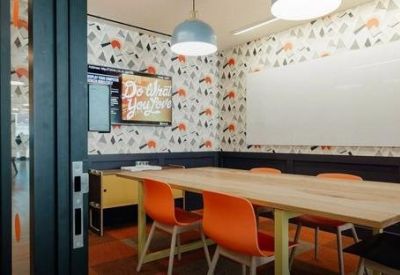 Meeting room with a long wooden table, orange chairs, and colourful patterned wallpaper.