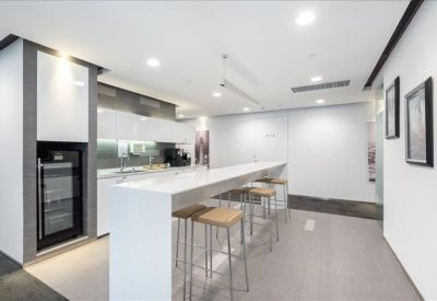 Modern communal kitchen area with a long white breakfast bar and tall stools.