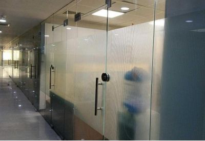 Glass-walled office corridor featuring frosted privacy film and sleek metal door handles.