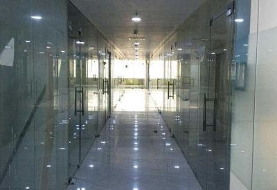 Bright, polished hallway lined with glass-partitioned office suites and recessed ceiling lights.