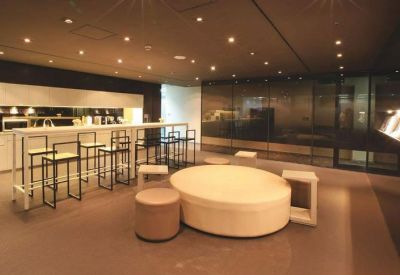 Contemporary communal lounge featuring a round central ottoman and high-top cafe seating.