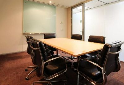 Small meeting room with a wooden table, black leather chairs, and a glass whiteboard.