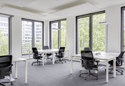 Bright open-plan workspace with white desks and floor-to-ceiling windows.