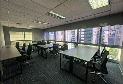 Spacious office area featuring rows of workstations and large windows with city views.