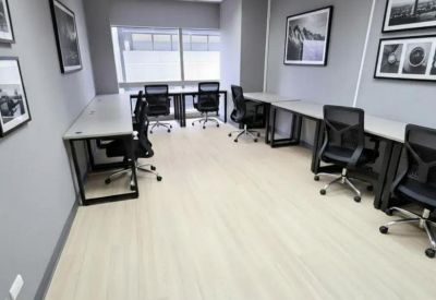 Bright office space with minimalist desks and framed landscape photography on grey walls.
