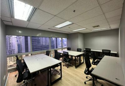Open office area featuring several white desks and light wood-style flooring.