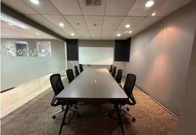 Team office space with multiple white desks, black chairs, and large windows.