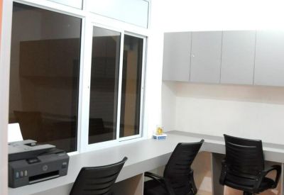 Internal office suite with black chairs, a built-in desk, and a large window overlooking the atrium.