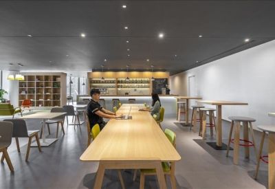 Spacious communal lounge with a high wooden table, bar stools, and floor-to-ceiling bookshelves.