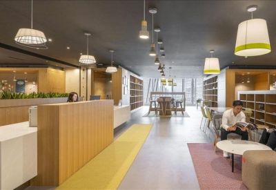 Warm reception area featuring a light wood desk, soft yellow accents, and hanging pendant lamps.