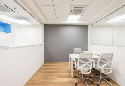Minimalist private office with white desks and grey feature wall.