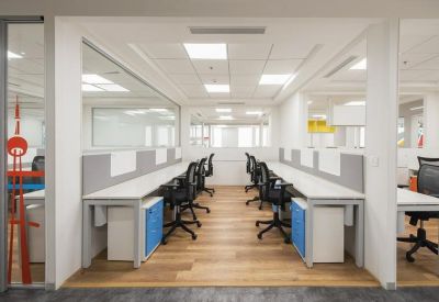 Open-plan workspace with rows of white desks and blue storage pedestals.