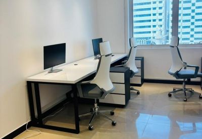 Modern office workspace featuring white desks, ergonomic chairs, and large windows with city views.