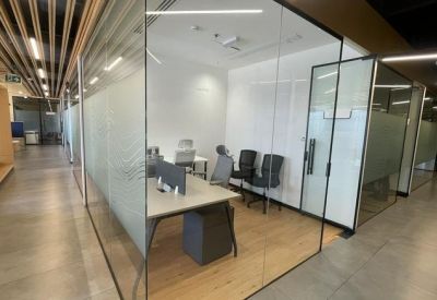 Glazed internal office suite with wooden flooring and minimalist grey furniture.