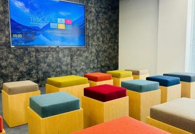 Vibrant breakout area with colorful cube seating and a large digital display screen.