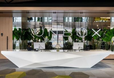Modern white reception desk with angular geometry and UNBOX branding against a mirrored wall.