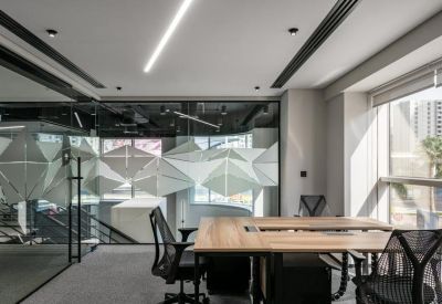 Bright workspace with a large wooden desk, ergonomic chairs, and geometric wall patterns.