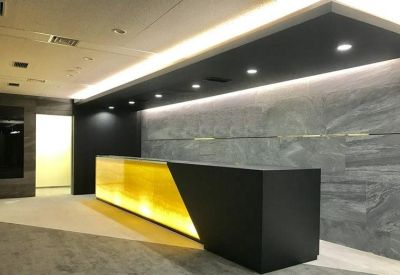 Sleek modern reception area with a glowing yellow desk and grey stone feature wall.