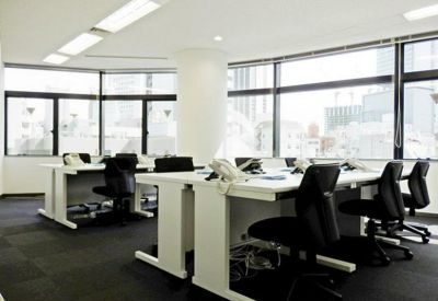 Bright open-plan office space featuring white desks and large windows with city views.