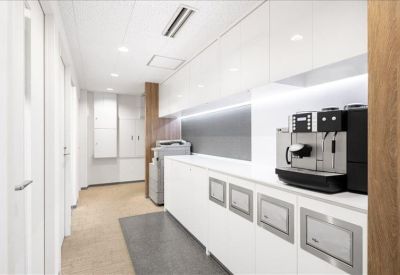 Clean white communal kitchen area featuring an espresso machine and storage cabinets.