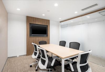 Bright conference room with a light wood table, black chairs, and a wall-mounted TV.