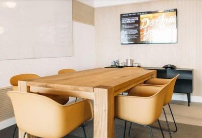 Bright meeting room with a large wooden table and beige bucket chairs.