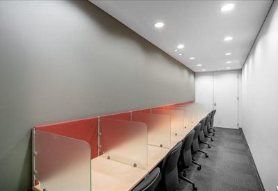 Row of individual workstations separated by frosted glass dividers in a quiet office setting.