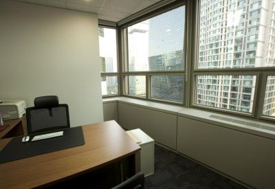 Private corner office suite with wooden desk and large windows overlooking the city.